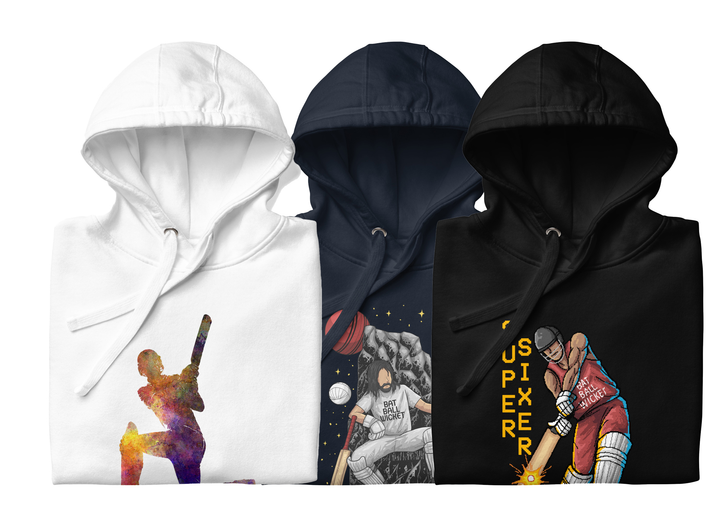 Three folded hoodies with cricket-themed designs: a white hoodie with a colorful silhouette of a batter, a navy hoodie with a batter on a throne and 'Bat Ball Wicket' text, and a black hoodie with a batter hitting a 'Super Sixer'.