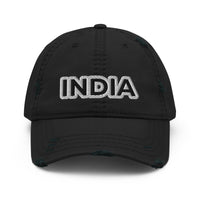 Full front view of the black distressed cap with 'INDIA' embroidered in white, set against a textured black background with distressed detailing.