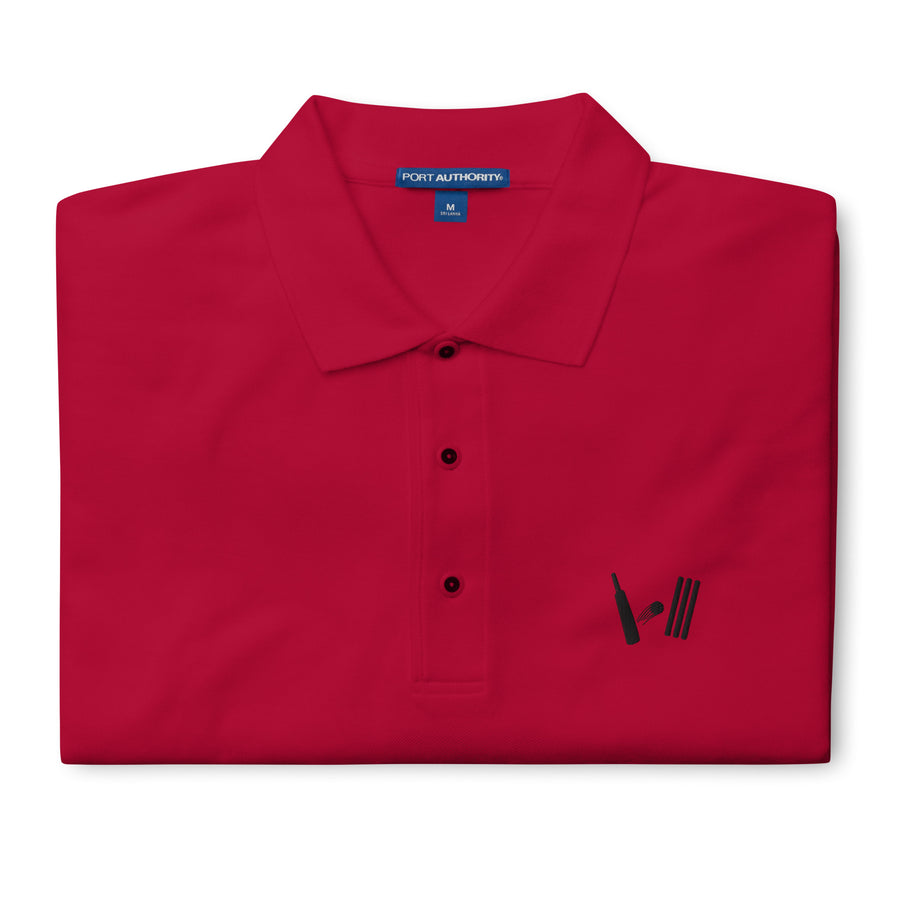 Vibrant red polo shirt folded neatly with the Bat Ball Wicket logo visible on the front, representing a bold cricket fashion statement