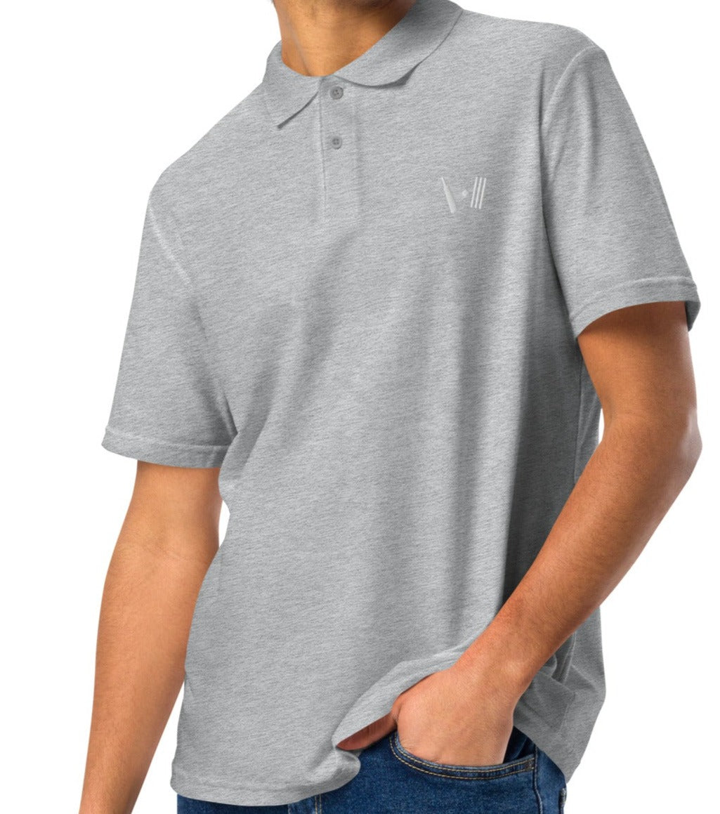 Casual grey polo shirt worn by a man, featuring a neat white embroidery of a cricket bat and stumps on the left chest, paired with blue jeans